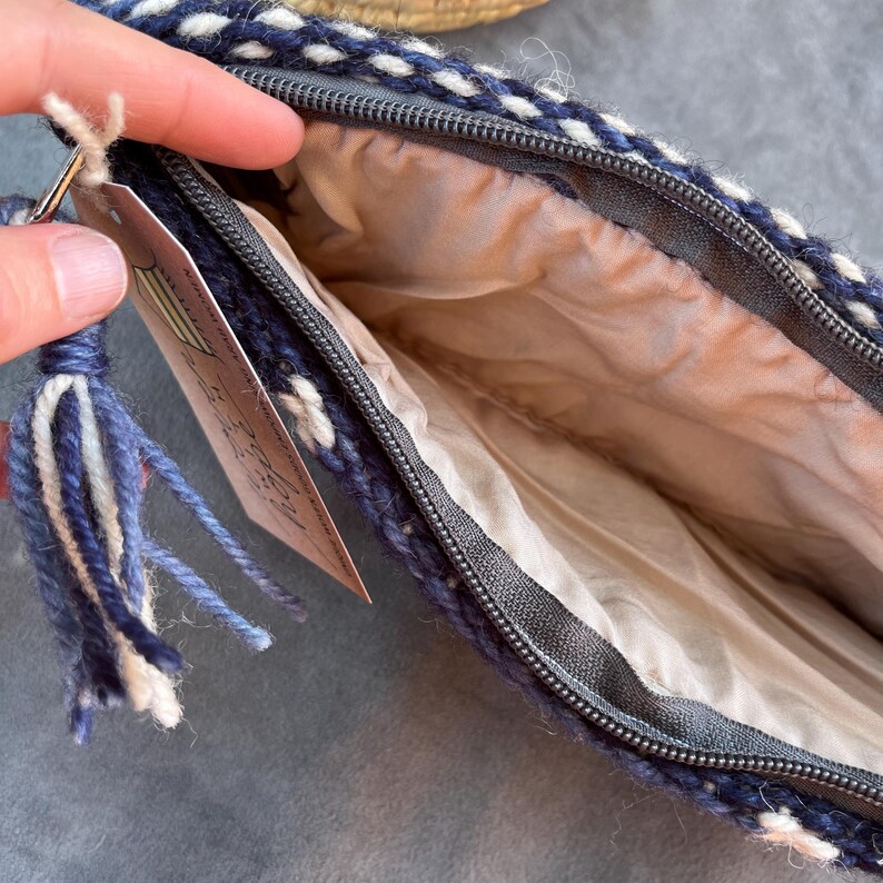 May include: A blue and white woven zippered pouch with a tassel. The pouch is lined with a beige fabric.