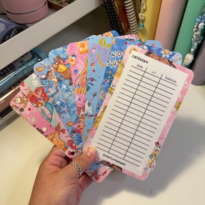 May include: A selection of colourful budget planner inserts with Disney character designs. The inserts have a pink and white border, with sections for category, date, +/- and balance. The text "BUDGETWITHAMANDA" is visible.