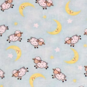 May include: Pale blue fabric featuring a repeating pattern of cartoon sheep, yellow crescent moons, and white stars. The sheep are white with brown faces and legs. The moons have smiling faces. The fabric is measured in inches.