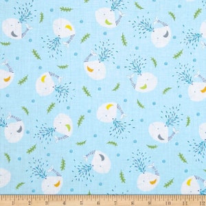May include: A light blue fabric with a repeating pattern of white whales blowing water. The whales are outlined in gray and have a yellow crescent moon on their backs. The background is dotted with small blue circles and green leaves.