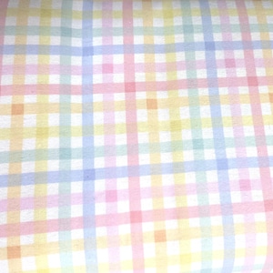 Könnte beinhalten: Ein Stoff mit einem sich wiederholenden Karomuster, das aus sich kreuzenden horizontalen und vertikalen Linien in sanften Pastelltönen wie Gelb, Rosa, Hellblau und Mintgrün auf weißem Grund besteht und ein Gitter aus kleinen Quadraten bildet.