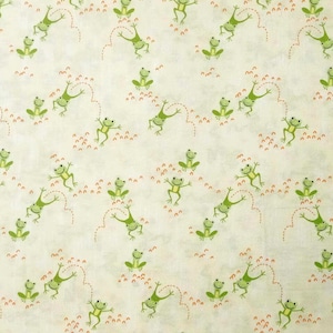 May include: A repeating pattern of cartoon frogs in various poses on a cream-colored background. The frogs are green with smiling faces and are interspersed with small orange dotted lines and clusters.