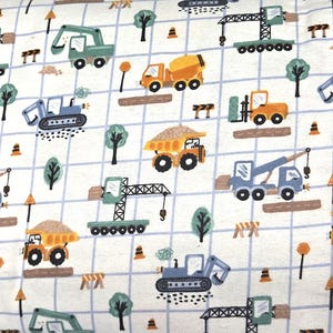 May include: A white fabric featuring a light blue grid pattern overlaid with a repeating print of construction vehicles including yellow dump trucks, blue excavators, and green cranes, interspersed with small green trees and orange traffic cones.