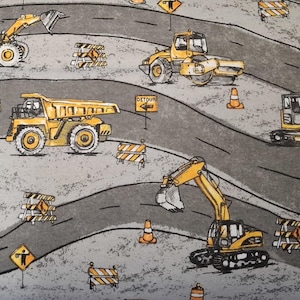 May include: A gray fabric featuring a construction site design. The pattern includes yellow construction vehicles like excavators, dump trucks, and road rollers. Orange traffic cones and detour signs are also present, creating a busy, active scene.