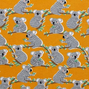 May include: A yellow fabric with a repeating pattern of gray koala bears on branches with green leaves. The koalas are facing different directions and have different poses.