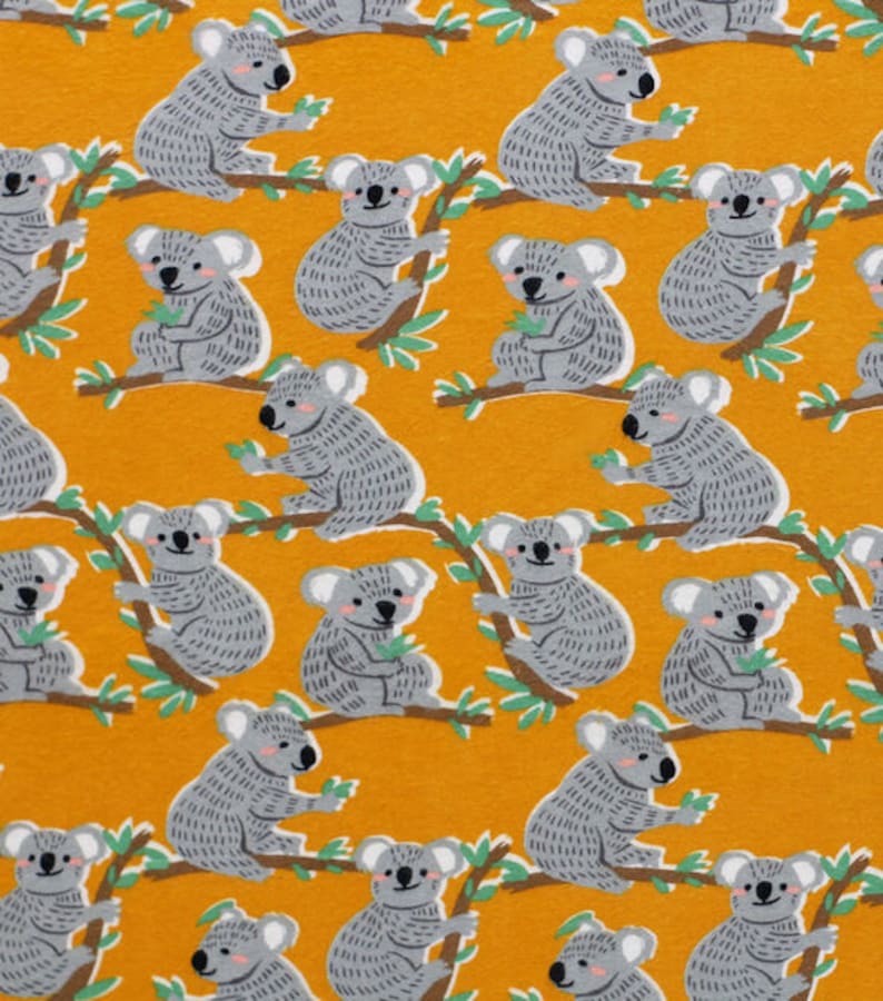 May include: A yellow fabric with a repeating pattern of gray koala bears on branches with green leaves. The koalas are facing different directions and have different poses.