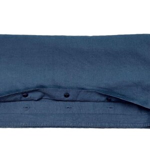 Op de afbeelding: Gevouwen donkerblauw button-down shirt. Het shirt is gemaakt van een zachte stof en heeft een klassieke kraag en manchetten met knopen. De knopen zijn zwart. Het shirt is netjes opgevouwen en toont de voorkant en een deel van de kraag.