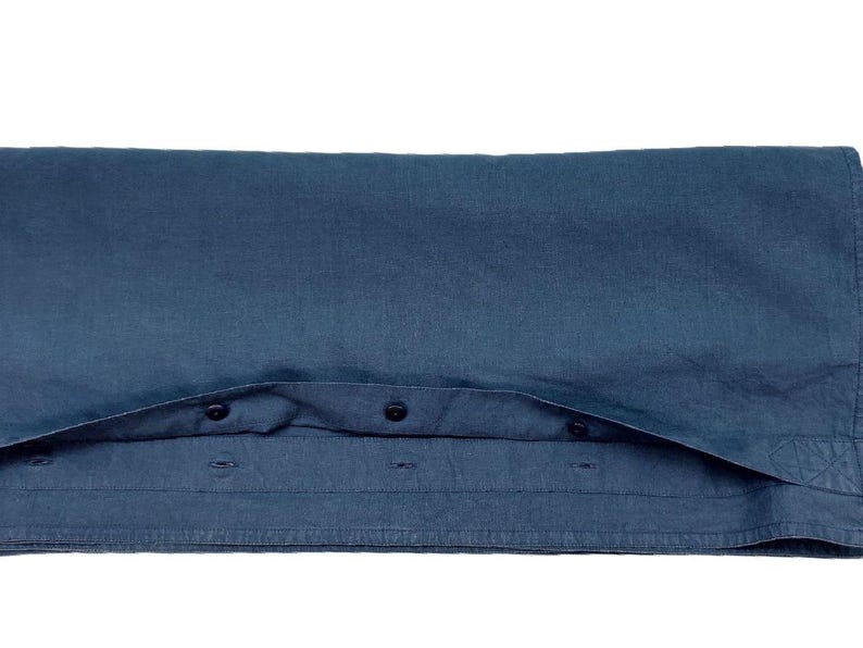 Op de afbeelding: Gevouwen donkerblauw button-down shirt. Het shirt is gemaakt van een zachte stof en heeft een klassieke kraag en manchetten met knopen. De knopen zijn zwart. Het shirt is netjes opgevouwen en toont de voorkant en een deel van de kraag.