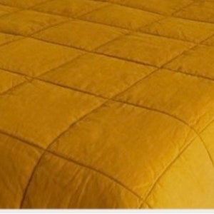 May include: A mustard yellow quilted bedspread with a square pattern.