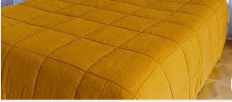 May include: A mustard yellow quilted bedspread with a square pattern.