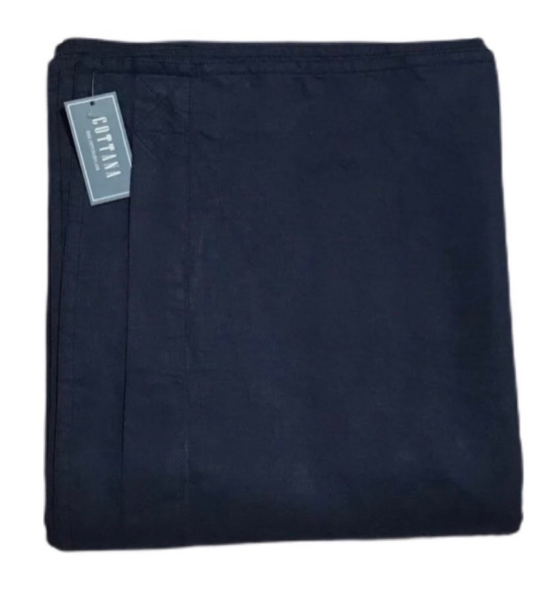 Op de afbeelding: Een gevouwen, marineblauwe stof met een label met de tekst "COTTANA". De stof lijkt glad te zijn en heeft een lichte glans. Het label is rechthoekig met witte tekst op een grijze achtergrond.