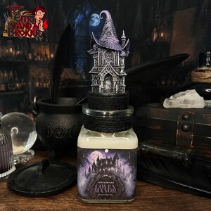 Peut inclure: Un pot décoratif avec un couvercle noir et une miniature détaillée d'une maison de sorcière sur le dessus. Le pot porte une étiquette avec une illustration de château gothique et le texte "Coven Manor". Le pot est rempli d'une substance de couleur claire.