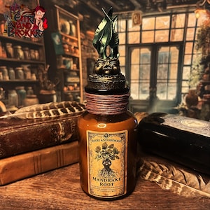 Può includere: Una piccola bottiglia di vetro con un'etichetta marrone che recita "YITTRI AND BROKKR MANDRAKE ROOT" e un tappo di bottiglia verde e oro a forma di radice di mandragola.