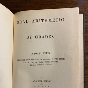 Könnte beinhalten: Ein Buch mit dem Titel "Oral Arithmetic by Grades Book Two", das für den Einsatz in der fünften, sechsten und siebten Klasse der Grundschule konzipiert wurde. Das Buch wurde von der American Book Company herausgegeben.