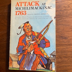 Può includere: Una copertina di libro vintage con un'illustrazione colorata di un uomo nativo americano che tiene un fucile. Il titolo del libro è "Attack at Michilimackinac 1763" e il sottotitolo è "a cura di David A. Armour".