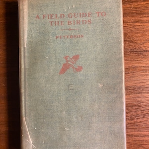 May include: A green hardback book titled "A Field Guide to the Birds" by Peterson. The book cover features a red illustration of a bird in flight.
