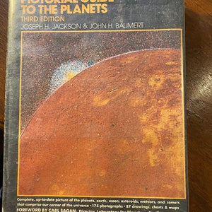 Op de afbeelding: Een boekomslag met een rode en oranje planeet op de voorkant. De titel is "Pictorial Guide to the Planets" en de ondertitel is "Third Edition". De auteurs zijn Joseph H. Jackson & John H. Baumert. Het boek bevat ook een voorwoord van Carl Sagan.