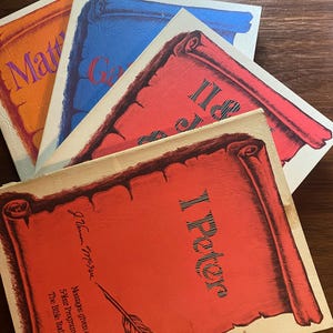 May include: A stack of four softcover booklets with scroll-shaped cover art. The top booklet is red with the text 'I Peter', 'J. Vernon McGee', and 'Messages given on the 5-Year Program of Thru The Bible Radio Network'. Other booklets are orange, blue, and red.
