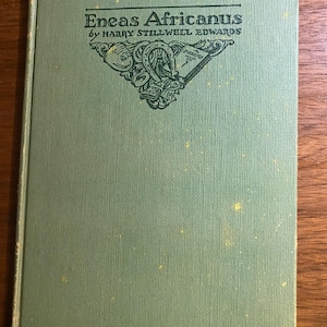 Könnte beinhalten: Ein Vintage-Buch mit dem Titel "Eneas Africanus" von Harry Stillwell Edwards. Das Buch hat einen hellgrünen Einband mit dem Titel und dem Namen des Autors in Dunkelgrün. Ein dekoratives Emblem ist ebenfalls auf dem Einband vorhanden.