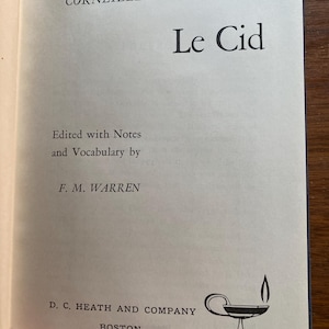 以下が含まれることがあります： 開かれた本のページで、コルネイユの「ル・シッド」というタイトルです。テキストはクリーム色のページに黒色で印刷されています。この本はF. M. Warrenによって編集され、D. C. Heath and Company, Bostonによって出版されました。下部に小さなランプのイラストがあります。