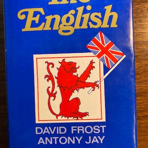 Könnte beinhalten: Ein blauer Buchumschlag mit dem Titel "The English" in goldenen Buchstaben. Der Umschlag zeigt außerdem einen roten Löwen mit einem Schwert und eine Union Jack-Flagge.