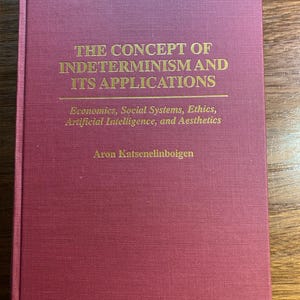 May include: A burgundy hardcover book with gold lettering on the front cover. The title is "The Concept of Indeterminism and Its Applications". The subtitle is "Economics, Social Systems, Ethics, Artificial Intelligence, and Aesthetics". The author's name is "Aron Katsenelinboigen".