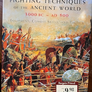 May include: A book cover with a painting of ancient warriors in battle. The title is "Fighting Techniques of the Ancient World 3000 BC - AD 500" and the subtitle is "Equipment, Combat Skills, and Tactics". The book is priced at $9.98.