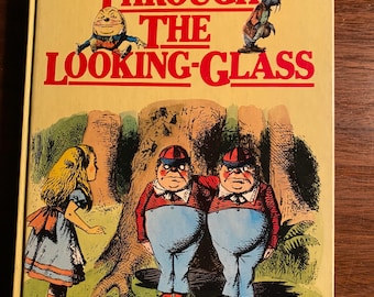 May include: A vintage hardcover book titled "Through the Looking-Glass" by Lewis Carroll. The cover features an illustration of Alice standing in a forest with two identical twins wearing red and blue striped shirts and hats.