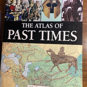 Puede incluir: Un libro titulado "THE ATLAS OF PAST TIMES" con una ilustración de mapa e imágenes históricas. El libro presenta un mapa con nombres geográficos y una representación de una figura montada a caballo. El nombre del autor, John Haywood, también es visible.