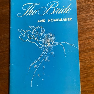 May include: A blue cover of a magazine titled "The Bride and Homemaker" with a white illustration of an angel holding a bouquet of flowers.