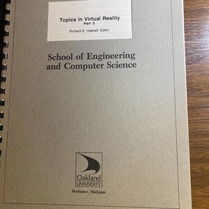 May include: A spiral-bound book with a gray cover. The title "Topics in Virtual Reality Part 3" is printed on a white rectangle. Below, the text reads "School of Engineering and Computer Science" and the Oakland University logo.