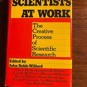 Pode incluir: Uma capa de livro vermelha e amarela com o título "Scientists at Work: The Creative Process of Scientific Research" e o nome "John Noble Wilford" como editor.