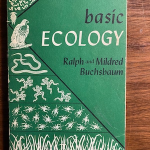 Puede incluir: Una cubierta de libro verde con el título "basic ECOLOGY" y los autores "Ralph and Mildred Buchsbaum". La cubierta presenta una ilustración estilizada de una cadena alimentaria con un halcón, una serpiente, ranas, grillos y hierba.