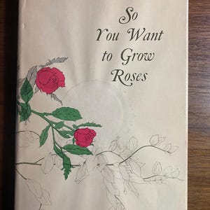 May include: A vintage book cover with the title "So You Want to Grow Roses" in elegant script. The cover features illustrations of red roses and green leaves, with a light beige background. The book appears to be an older edition.