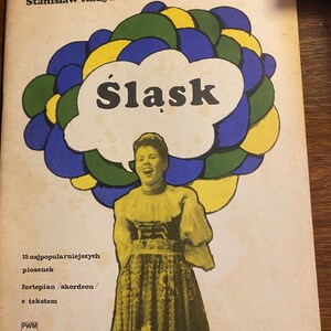 Puede incluir: Una portada de libro con una ilustración colorida de una mujer cantando. El título del libro es "Śląsk" y el autor es Stanisław Hadyna. El libro es una colección de 15 canciones populares para piano o acordeón con letras.