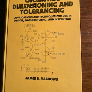May include: A yellow book cover with the title "Geometric Dimensioning and Tolerancing" in black text. The book cover also includes a black and white diagram of a mechanical part with various dimensions and tolerances labeled. The author's name, "James D. Meadows", is printed in black text at the bottom of the cover.