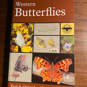 May include: A book titled "Western Butterflies" by Paul A. Opler and Amy Bartlett Wright. The cover features a variety of colorful butterflies, including a swallowtail, a fritillary, and a monarch.