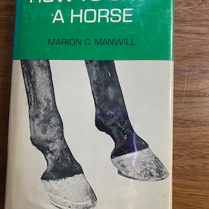 Puede incluir: Un libro antiguo titulado "HOW TO SHOE A HORSE" de Marion C. Manwill. La portada presenta una sección superior verde con texto blanco y una imagen en blanco y negro de dos cascos de caballo.