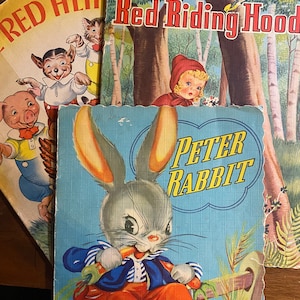 May include: Three vintage children's books with colorful illustrations. The books are titled "Red Hen", "Little Red Riding Hood", and "Peter Rabbit".