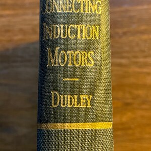 May include: A green book with gold lettering on the spine. The title is "Connecting Induction Motors" by Dudley.