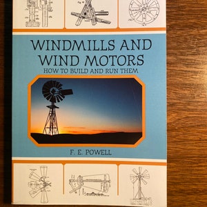 May include: A blue book titled "Windmills and Wind Motors: How to Build and Run Them" by F. E. Powell. The cover features a vintage illustration of a windmill against a sunset sky.