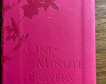 May include: A hot pink journal with embossed floral design and the text "ONE-MINUTE PRAYERS for Women". The journal has a ribbon bookmark. The cover is a solid, vibrant pink color.