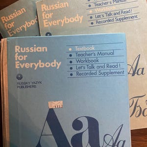 May include: Several vintage Russian language textbooks, titled "Russian for Everybody." The books are in shades of blue and tan, with white text. The cover of the main book features large blue Cyrillic letters. The books include a textbook, teacher's manual, and workbook.