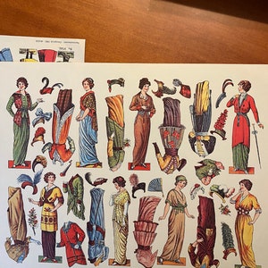 May include: A vintage paper doll set featuring women in various outfits and accessories. The dolls are dressed in colourful dresses, hats, and shoes. The set includes a variety of accessories, such as purses, fans, and parasols. The paper dolls are printed on a cream-coloured background.