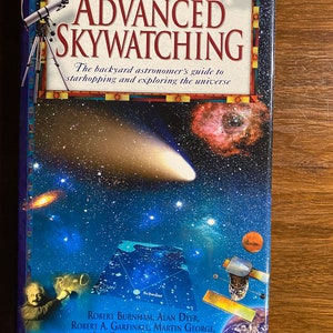 May include: A hardcover book titled "Advanced Skywatching" with a space-themed cover. The cover features a telescope, planets, and a starry background. The book is a guide to starhopping and exploring the universe.