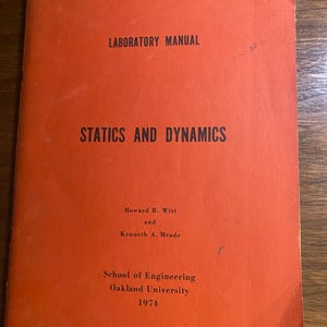 May include: A vintage orange book titled "STATICS AND DYNAMICS." The cover reads "LABORATORY MANUAL" and lists authors Howard R. Witt and Kenneth A. Meade. Published by Oakland University's School of Engineering in 1974.