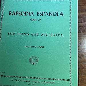 Puede incluir: Una partitura verde para "Rapsodia Española, Opus 70" de Albéniz, para piano y orquesta. La portada presenta texto negro, incluyendo el nombre de la editorial, International Music Company, y la ubicación, Nueva York.