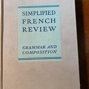 Puede incluir: Un libro vintage titulado "Simplified French Review Grammar and Composition" con una cubierta azul claro y blanca.