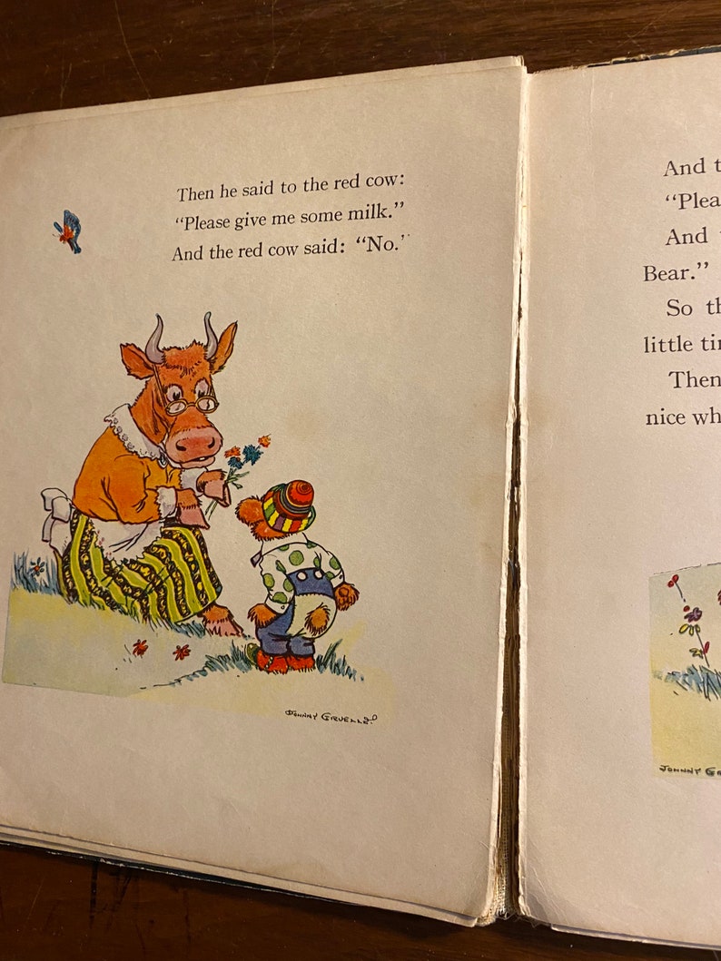 K&ouml;nnte beinhalten: Eine rote Kuh mit einer gelb-gr&uuml;n gestreiften Sch&uuml;rze und Brille sagt "Nein" zu einem kleinen B&auml;ren, der ein blaues und gr&uuml;nes Outfit und einen rot-gelben Hut tr&auml;gt. Der Text lautet "Then he said to the red cow: "Please give me some milk." And the red cow said: "No."
