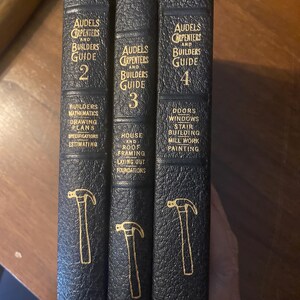 May include: Three vintage hardcover books titled "Audels Carpenters and Builders Guide" with gold lettering and hammer illustrations. The books are dark blue and feature topics like building, mathematics, and framing.
